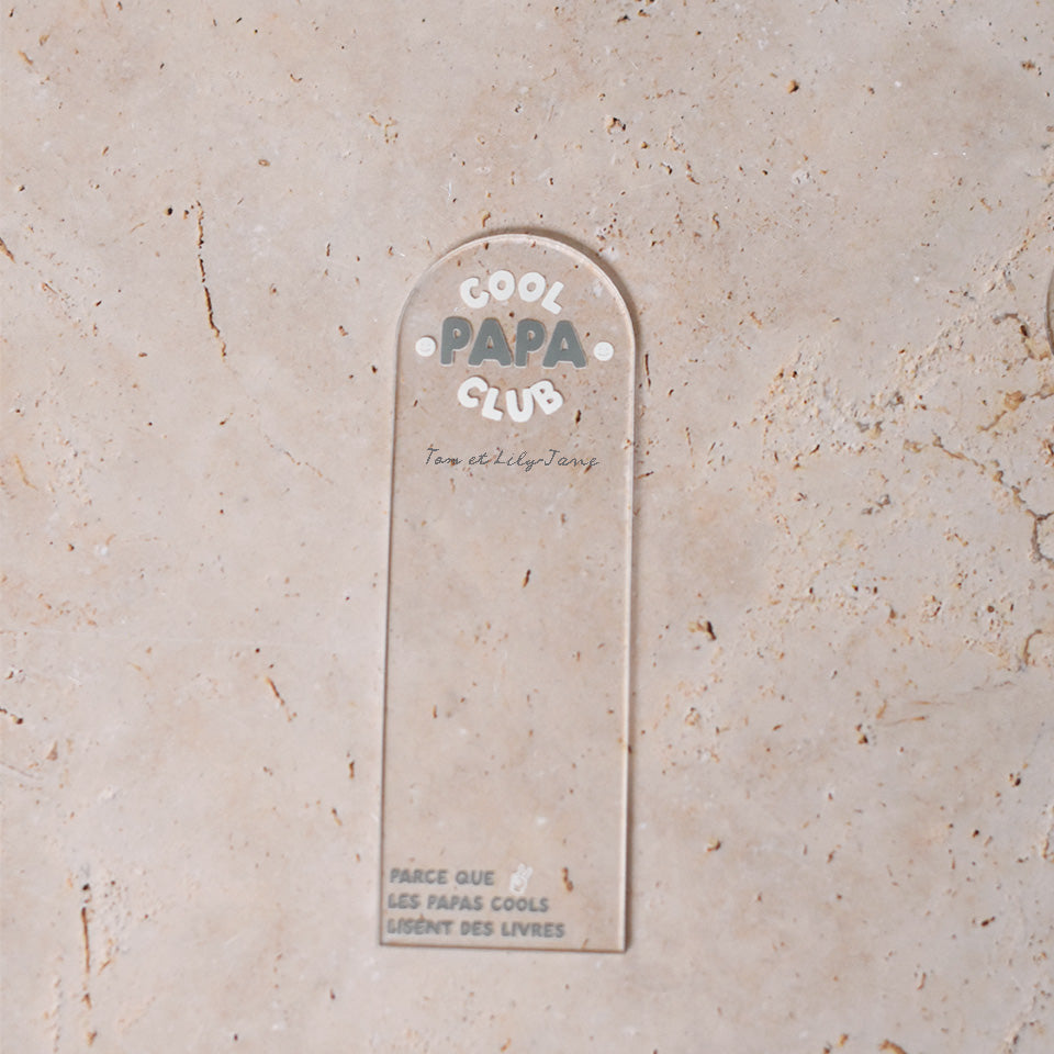 Marque-pages en plexi transparent découpe forme arche, texte blanc et vert. Inscription dans l’arche sur 3 lignes « Cool Papa Club », 2 smiley entourent le mot « PAPA ». Les mots « cool » et « club » et les motifs sont inscrits en blanc, le reste du texte est en couleur.
En dessous est inscrit un prénoms (personnalisation du produit)
En bas du marque-page est inscrit « Parque les papas cools lisent des livres » disposé sur 3 lignes avec un dessin de main en « v »