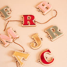 Plusieurs lettres en bois et relief plexi coloré (alternance miroir or, rouge, rose et vert) 
Il y a un  trou de chaque côté la découpe du lettrage, une cordelette y est pasée