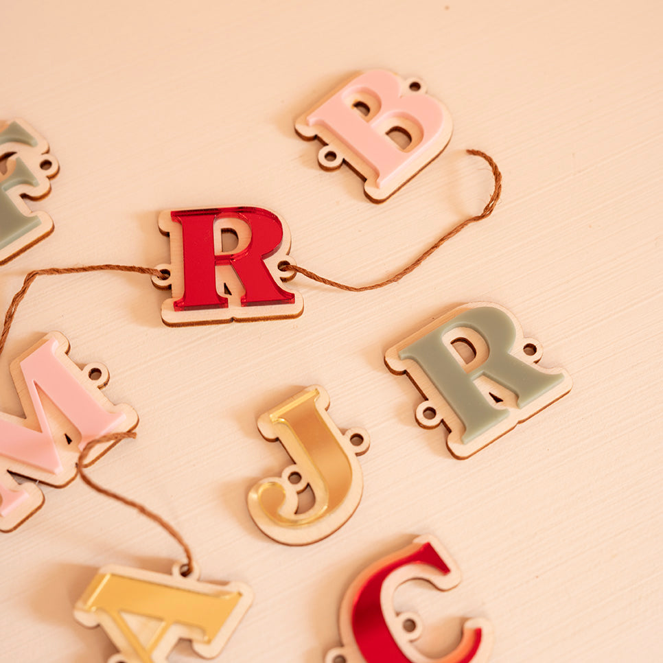 Plusieurs lettres en bois et relief plexi coloré (alternance miroir or, rouge, rose et vert) 
Il y a un  trou de chaque côté la découpe du lettrage, une cordelette y est pasée