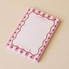 Bloc-notes papier 
Portrait rectangulaire
Modèle cadre rayé rose, contour vague rouge, coeurs rouges
Inscription haut sur 2 lignes « Mémodoux pour maman » 
Inscription bas « jusqu’au étoiles »
12 lignes à intervale réguliers 