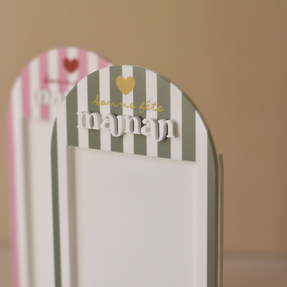 Cadre en plexiglass blanc
Modèle rayé vert et texte doré
Découpe forme arche sur socle blanc
Impression : rayures verticales, partie demi-cercle personnalisé avec inscription sur 3 ligne d’un coeur de « bonne fête » et de  « maman ».
Mot « maman » en relief plexi blanc
Inscription sur le bas du cadre de la phrase « reine de mon coeur » (phrase personnalisable)
Focus inscription et relief
