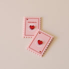 Magnet en plexi coloré rose et rouge, design de carte à jour, forme de timbre et coeur au centre en relief.  Inscription maman je t’aime ou reine de mon coeur 